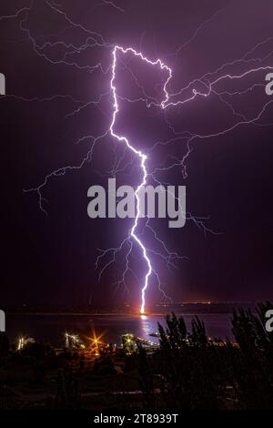 Nächtliche Blitze treffen auf den Pier am gegenüberliegenden Ufer des Flusses Stockfoto