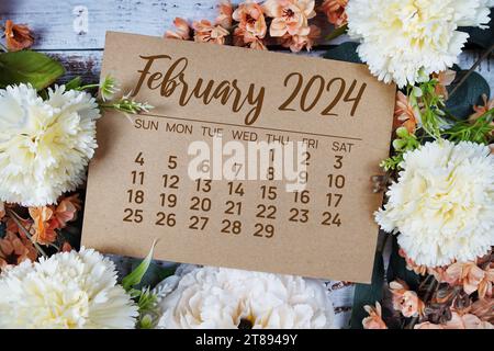 Monatskalender Februar 2024 mit Blumenstrauß Dekoration auf hölzernem Hintergrund Stockfoto