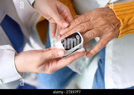 Doktor, der den Puls von einer Seniorin im Pflegeheim nimmt, Nahaufnahme Stockfoto