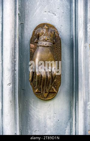 Hintergrund einer alten blauen Holztür mit einem bronzenen Griff in Form einer Hand mit einem Stern von David. Stockfoto