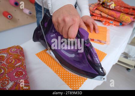 Nahaufnahme einer Frau, die Kleidung auf dem Bügelbrett bügelt Stockfoto