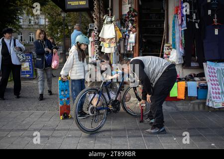 Belgrad, Serbien, 7. November 2023: Ein Verkäufer aus einem lokalen Geschäft hilft einem Mann mit einer Tochter, ein Fahrrad zu reparieren Stockfoto