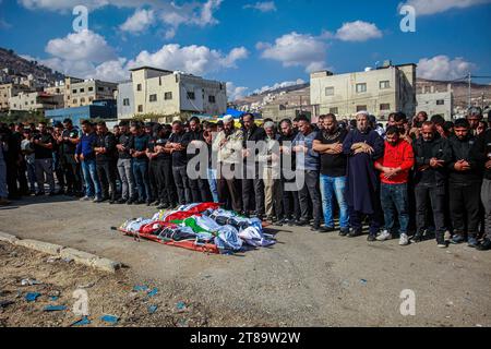 Nablus, Palästina. November 2023. (ANMERKUNG DER REDAKTION: Bild zeigt den Tod)Trauernde beten neben Leichen, die mit palästinensischen Fahnen bedeckt sind, während ihrer Beerdigung im Flüchtlingslager Balata im besetzten Westjordanland. Das israelische Militär sagte, dass sein Flugzeug ein Versteck für Militante im städtischen Flüchtlingslager Balata angegriffen habe. Der palästinensische Ambulanzdienst des Roten Halbmonds sagte, fünf Palästinenser seien beim Streik getötet worden. Quelle: SOPA Images Limited/Alamy Live News Stockfoto