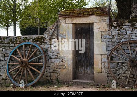 Une roue de charrette appuyée sur un mur en pierre / ein Rad auf einer Steinmauer Stockfoto