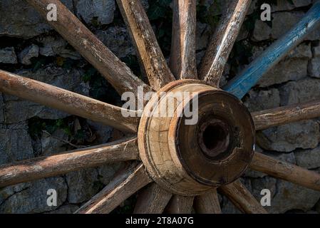 Une roue de charrette appuyée sur un mur en pierre / ein Rad auf einer Steinmauer Stockfoto