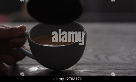 Gießen Sie gestreamte Milch in eine blaue Tasse, um Cappuccino mit Platz zum Kopieren und breitem Foto zuzubereiten Stockfoto