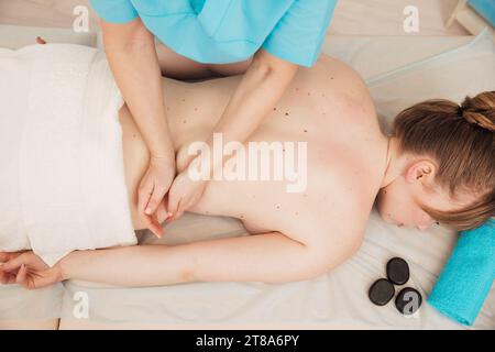 Handmasseur-Rückenmassage auf der Liege zur Entspannungs-Osteopathie der Frau Stockfoto