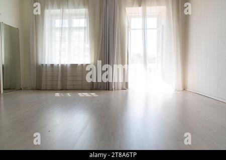 Großes helles Zimmer mit Fenster und Vorhängen im Apartment Stockfoto