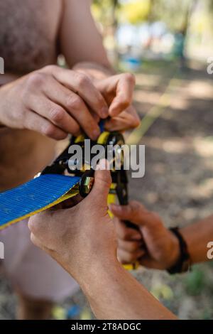 Zwei Männer, die während des Sommertages im Stadtpark Slackline-Ausrüstung aufstellen Stockfoto