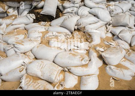 Stapel von Sandsäcken und Sand, die für den Einsatz bei Hochwasser bereit sind. Stockfoto