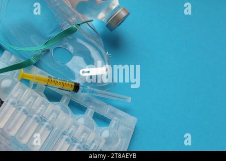 Coronavirus-Behandlungskonzept. Ein medizinischer Gesichtsmasken-Vernebler für die Behandlung der Atemwege und Ampullen flach auf blauem Hintergrund gelegt. Kopierbereich Stockfoto