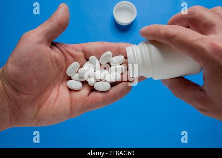 Die Hand gießt Pillen in die Handfläche. Stockfoto