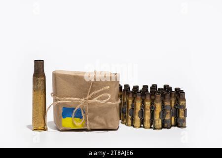 Neben einer Box, auf der die Flagge der Ukraine gemalt ist, stehen ein automatisches Gewehrgehäuse und ein Band mit Kugellandschaften, humanitäre Hilfe in Form o Stockfoto