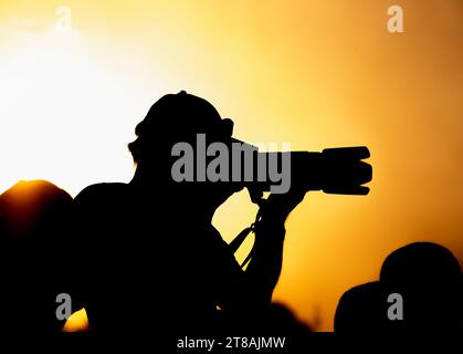 Eine Silhouette eines Fotografen mit einer Kamera bei Sonnenuntergang. Stockfoto