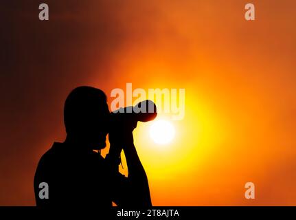 Eine Silhouette eines Fotografen mit einer Kamera bei Sonnenuntergang. Stockfoto