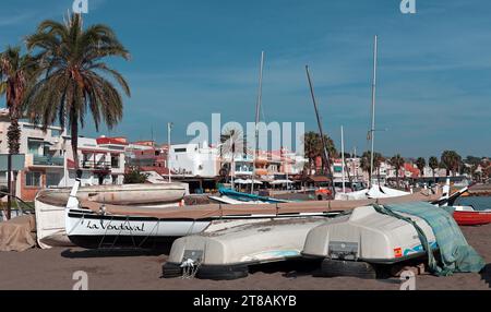 Fischerdorf Pedregalejo, Malaga: Fischerboote sitzen auf dem Sand um eine der Buchten am Strand von Pedgregalejo vor der Strandpromenade Stockfoto