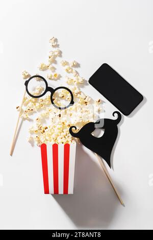 Köstliches Popcorn, Partyrequisiten und Smartphone mit leerem Bildschirm für Ihr Design Stockfoto