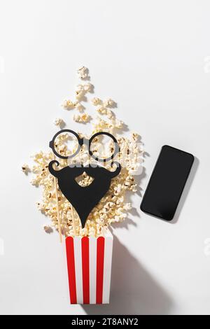 Köstliches Popcorn, Partyrequisiten und Smartphone mit leerem Bildschirm für Ihr Design Stockfoto