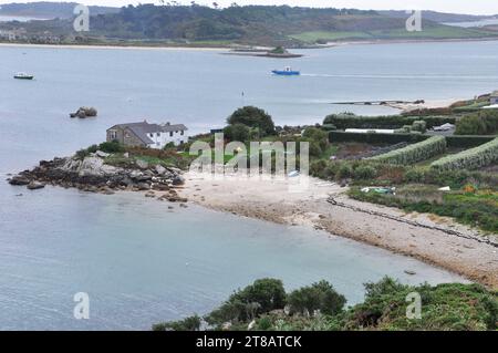 Blick vom Shipman Fahren Sie hinunter auf die Insel Bryher über den Küchenhafen und die Stadt in Richtung Tresco im Hintergrund. Eines der Inter-Island-Boote fährt Stockfoto