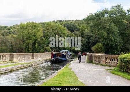 Schmalboot und Radfahrer auf dem Dundas Aqueduct, der den Kennet und Avon Kanal über den Fluss Avon und die Wessex Main Line Bahn führt. England, Großbritannien Stockfoto