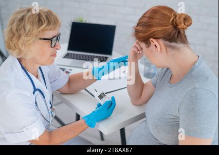 Eine schwangere Frau weint während eines Arztbesuchs. Schwangerschaftsdiabetes. Stockfoto