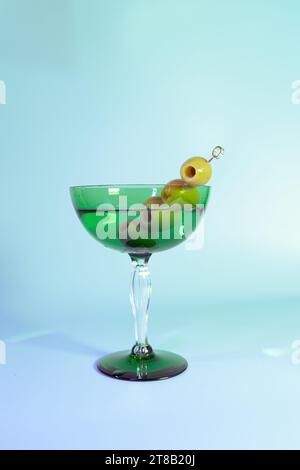 Elegantes Art déco-Martini mit Oliven in einem grünen Vintage-Glas Stockfoto