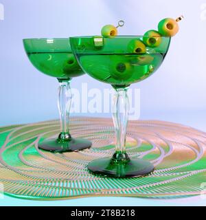 Ein Paar von Art déco-inspirierten schmutzigen Martinis in einem grünen Coupé-Glas mit Oliven Stockfoto