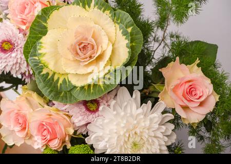 Blumenstrauß mit rosafarbenen Rosen, Brassica-Blüten, Chrysanthemen und Freesien-Blüten als Hintergrund. Stockfoto