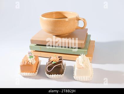 Buch und Frühstück: Eine Tasse Espresso und Mini-Gebäck auf einem Bücherstapel Stockfoto