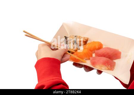 Lieferung von Lebensmitteln. Eine Schachtel mit Sushi-Rollen in Frauenhänden isoliert auf weißem Hintergrund. Stockfoto