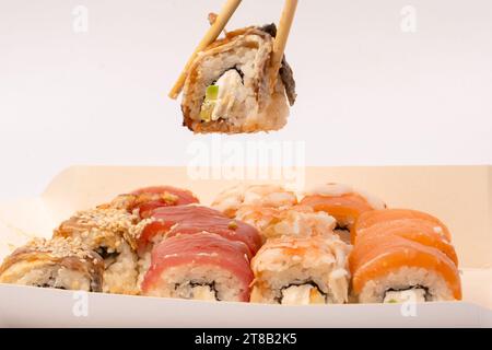 Lieferung von Lebensmitteln. Eine Schachtel mit Sushi-Rollen in Frauenhänden isoliert auf weißem Hintergrund. Stockfoto