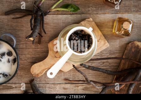 Hausgemachte Beinwell-Wurzelsalbe, die durch ein Sieb gestreut wird Stockfoto