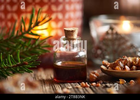 Ätherisches Myrrhenöl in einer Glasflasche mit Kerze zu Weihnachten Stockfoto