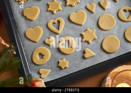 Verschiedene Formen aus Teig auf einem Blatt Backpapier - Vorbereitung von Linzer Weihnachtskeksen Stockfoto