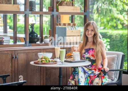 Eine junge Frau im Blumenkleid, die Gourmet-Essen genießt Stockfoto