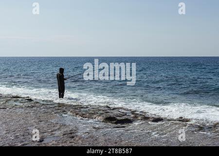 Ein Mann fischt im Meer oder Fluss in einem Gummianzug mit einer Angelrute Stockfoto