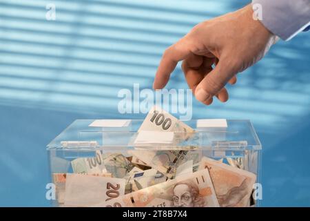 Wohltätigkeits- und Geldgeld CZK tschechische Kronen-Banknoten in eine transparente Spendenbox zur Geldspende. Eine finanzielle Unterstützung, sammelt Geld für einen edlen Zweck. Stockfoto