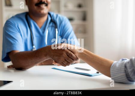 Doktor Mann Trägt Blaue Uniform Und Schüttelt Hände Mit Weiblicher Patientin In Der Klinik Stockfoto