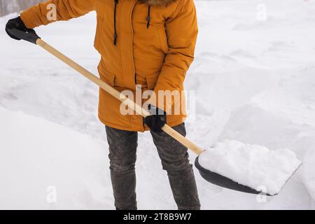 Nahaufnahme Mann reinigt und räumt den Schnee vor dem Haus an frostigen Tagen. Reinigung der Straße von Schnee an einem Wintertag. Schneefall und heftig Stockfoto