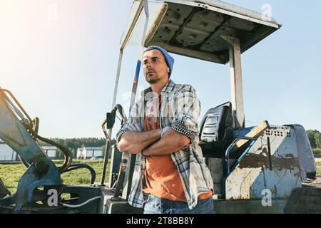 Junger Mann, der bei der Arbeit auf einer Baustelle in der Nähe seines alten Baggers steht Stockfoto
