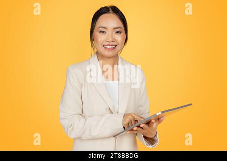 Positive selbstbewusste junge japanische Geschäftsfrau im Anzug, mit Tablet Stockfoto