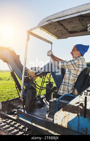 Junger Mann und sein alter Bagger bei Baustellenarbeiten Stockfoto