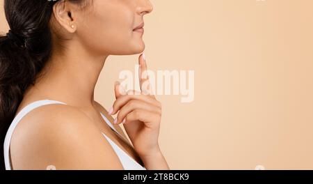 Kinnvergrößerung. Seitenaufnahme einer nicht erkennbaren jungen Frau, die ihr Gesicht berührt Stockfoto