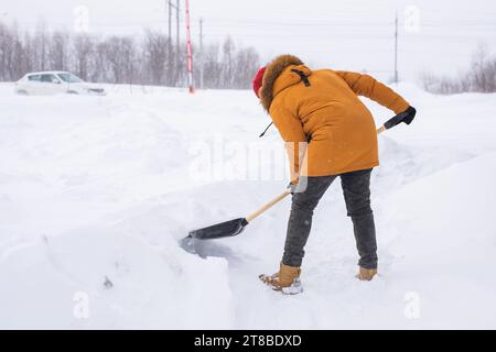 Mann, der Schnee vom Bürgersteig reinigt und Schneeschaufel benutzt. Wintersaison Stockfoto