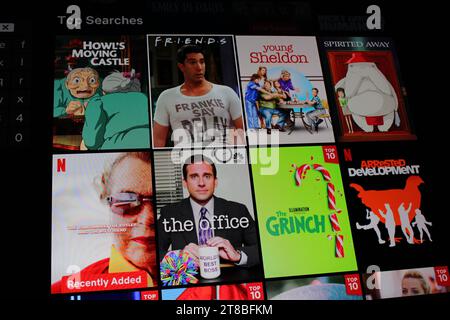Netflix-App auf dem Fernsehbildschirm, die Top-Suchanfragen wie Freunde, Young Sheldon, das Büro, verhaftete Entwicklung zeigt Stockfoto