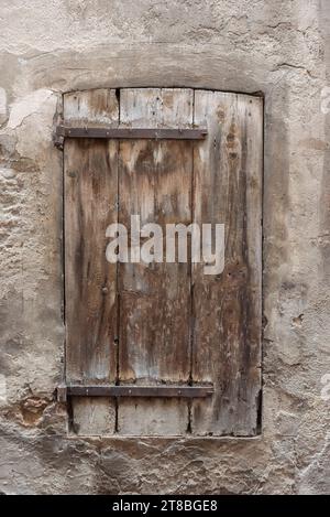 Alte und verwelkte Holzläden mit Eisenscharnieren, die mit Nägeln am Holz befestigt sind Stockfoto