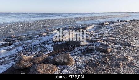 Schmelzende Eisschollen liegen an der gefrorenen Ostseeküste auf einem natürlichen Winterhintergrund Stockfoto