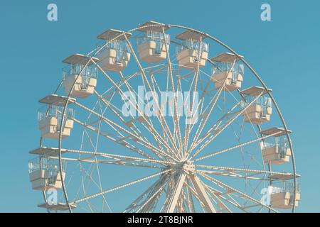 Das riesige weiße Riesenrad für Panoramablick im Vergnügungspark ist eine beliebte unterhaltsame Fahrt, die am hellen, sonnigen Tag am blauen Himmel geschossen wird Stockfoto