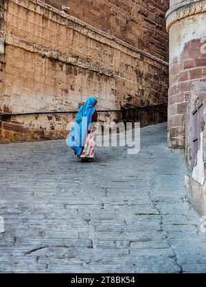 JODHPUR, INDIEN – 30. DEZEMBER 2022: Eine anonyme Frau geht die Rampe hinauf zum inneren Eingang des Mehrangarh-Forts Jodhspur, Indien. Stockfoto