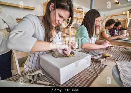 Gruppe von Leuten, die Keramikhandwerk in einem Töpferkurs machen. Hobby- und Bastelkonzept. Stockfoto